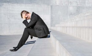 Businessman sitting on concrete steps with head in hands